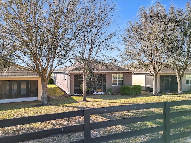 single story home featuring a front lawn, fence, a sunroom, and stucco siding