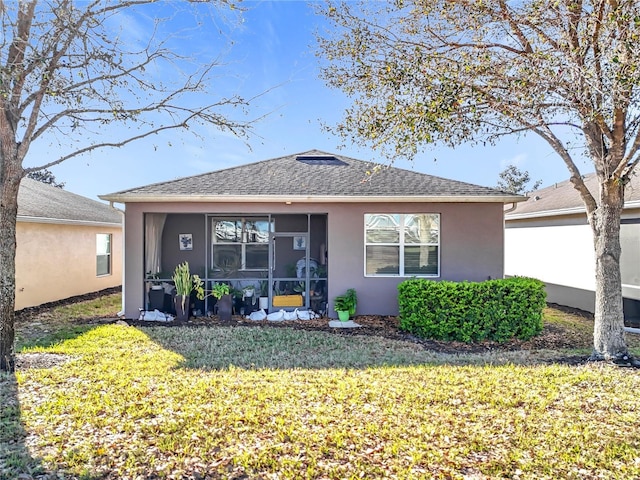 back of property with a shingled roof, a lawn, and stucco siding