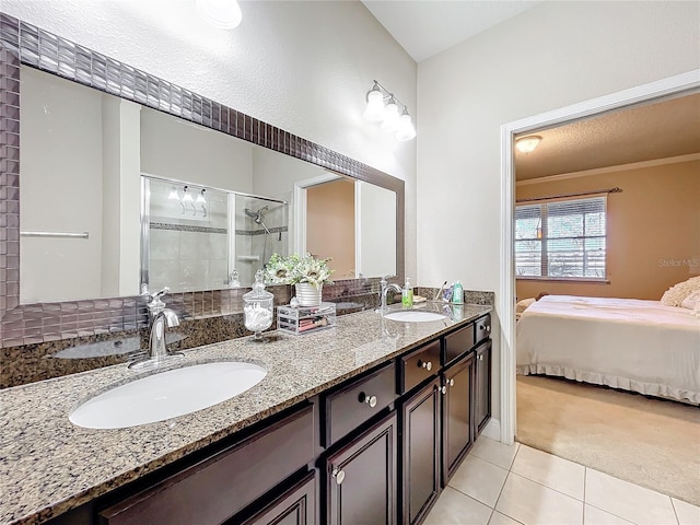 ensuite bathroom with a sink, double vanity, ensuite bath, and tile patterned floors