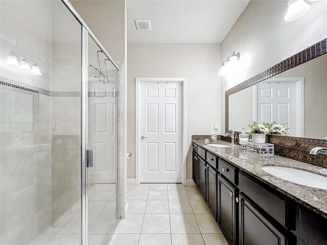 full bathroom with a textured ceiling, a stall shower, a sink, and visible vents