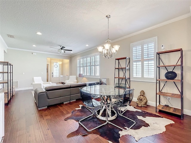 dining space with a textured ceiling, visible vents, baseboards, ornamental molding, and dark wood finished floors