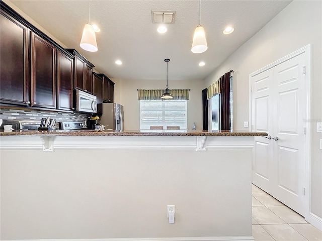 kitchen with light tile patterned floors, visible vents, a breakfast bar area, decorative light fixtures, and stainless steel appliances