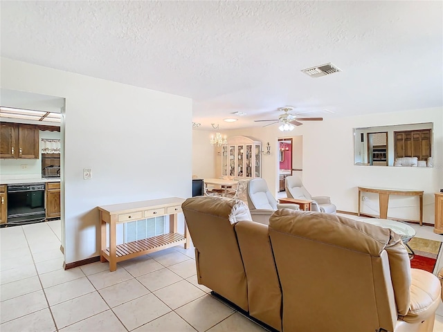 tiled living room featuring ceiling fan with notable chandelier and a textured ceiling