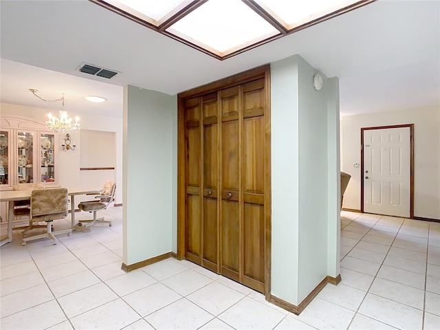 hall with a notable chandelier and light tile patterned floors