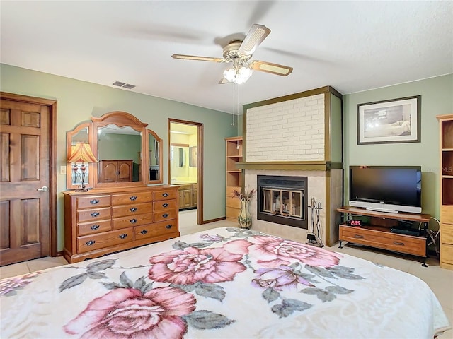 tiled bedroom with a large fireplace, connected bathroom, and ceiling fan