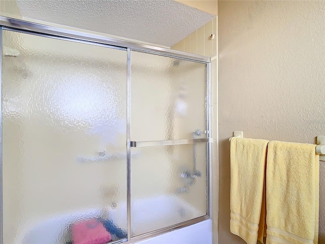 bathroom featuring enclosed tub / shower combo and a textured ceiling