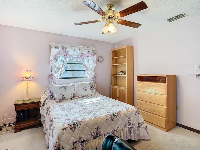 carpeted bedroom featuring ceiling fan and a textured ceiling