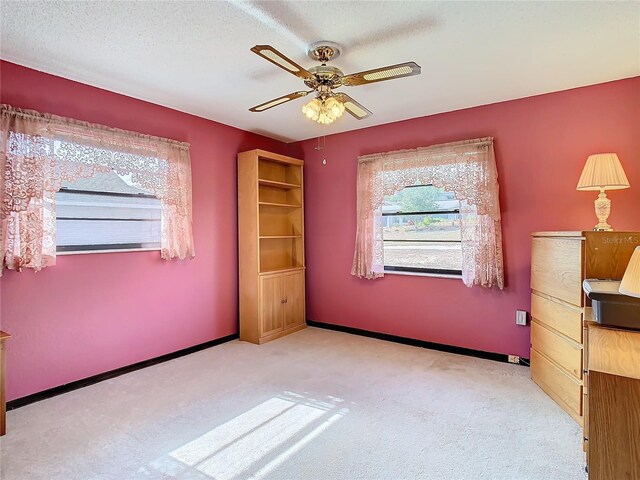 unfurnished bedroom featuring ceiling fan, light colored carpet, and a textured ceiling