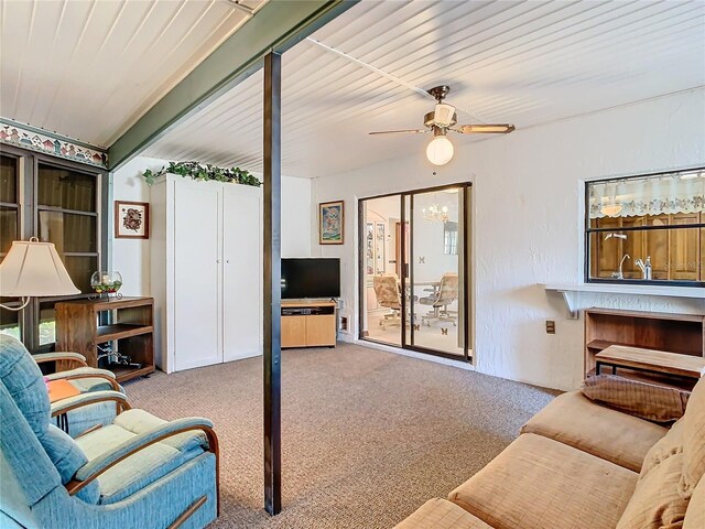 living room featuring ceiling fan, light colored carpet, and beamed ceiling