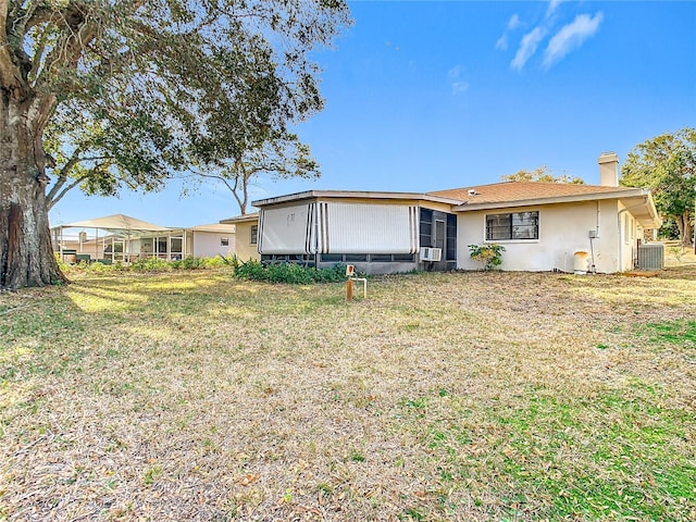 view of front of home featuring cooling unit, a front yard, and central air condition unit