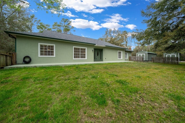 back of property with a yard, a storage unit, and a patio area