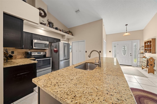 kitchen featuring light stone countertops, appliances with stainless steel finishes, sink, and pendant lighting