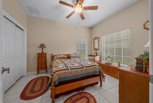 bedroom with ceiling fan, a textured ceiling, a closet, and light tile patterned floors