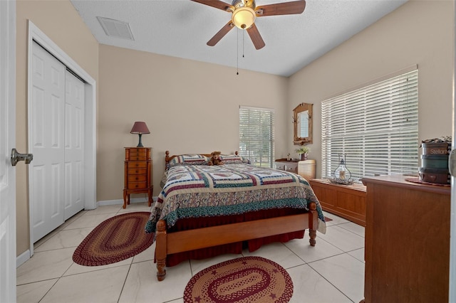 bedroom featuring light tile patterned flooring, a textured ceiling, ceiling fan, and a closet