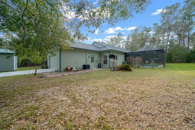 view of front of house featuring a garage, a front lawn, central air condition unit, and glass enclosure