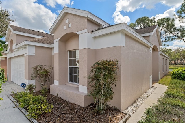 view of home's exterior featuring roof with shingles, an attached garage, and stucco siding