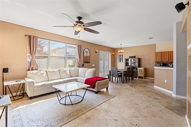 living room with ceiling fan with notable chandelier