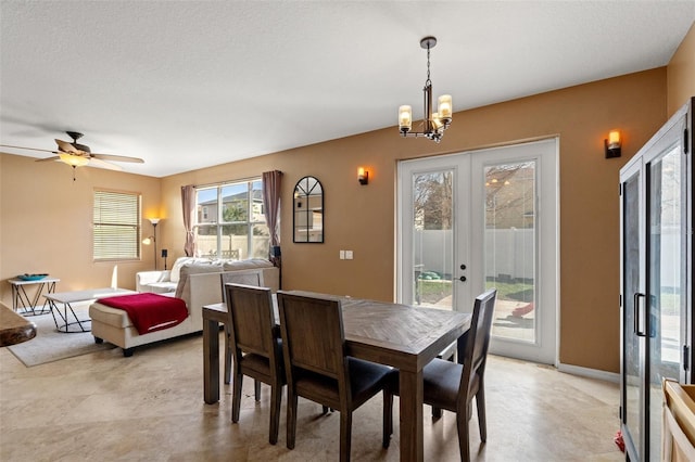 dining area featuring ceiling fan with notable chandelier, french doors, and a textured ceiling