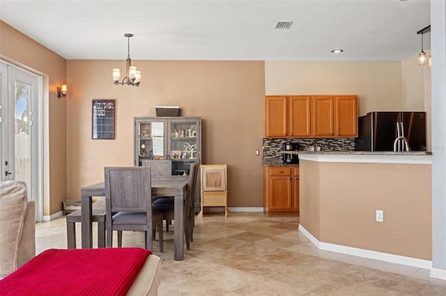 kitchen with fridge, a chandelier, hanging light fixtures, and backsplash