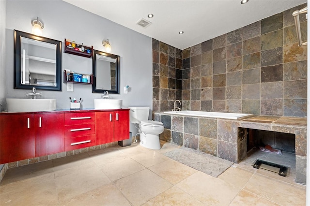 bathroom featuring vanity, a relaxing tiled tub, tile patterned floors, and toilet