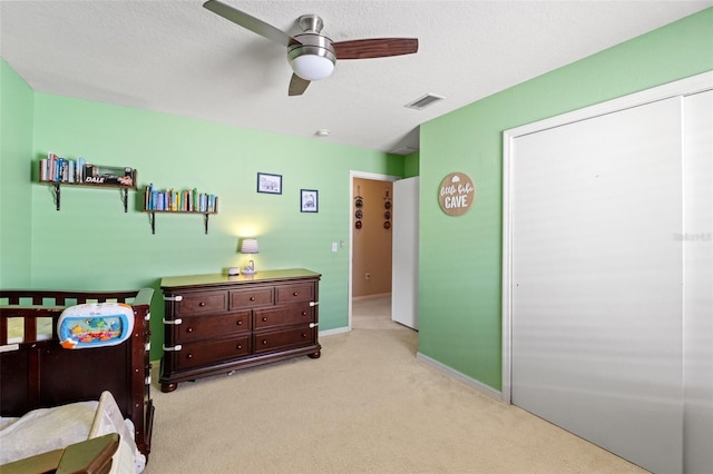 carpeted bedroom with a textured ceiling, ceiling fan, and a closet