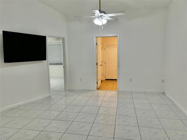 tiled spare room with ceiling fan