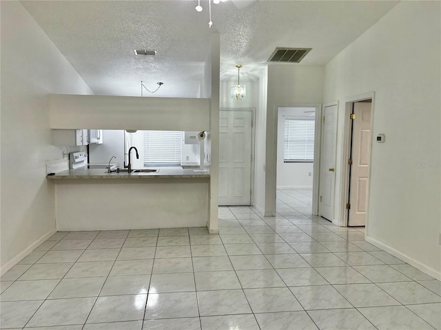 kitchen with light tile patterned flooring, sink, hanging light fixtures, kitchen peninsula, and a textured ceiling