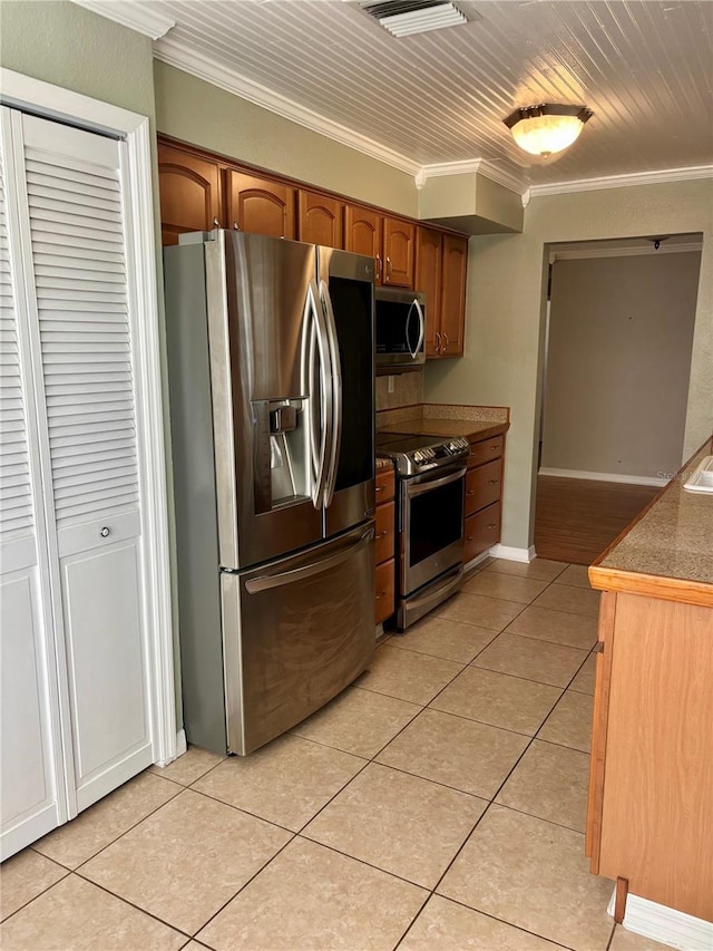 kitchen featuring crown molding, appliances with stainless steel finishes, and light tile patterned floors