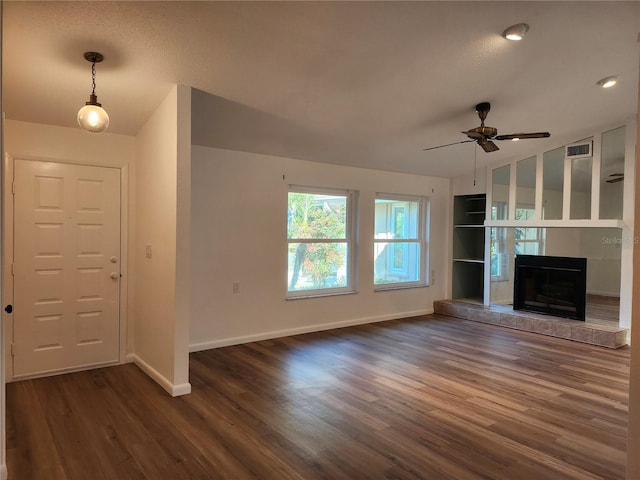 unfurnished living room featuring dark wood-type flooring, ceiling fan, and a tile fireplace