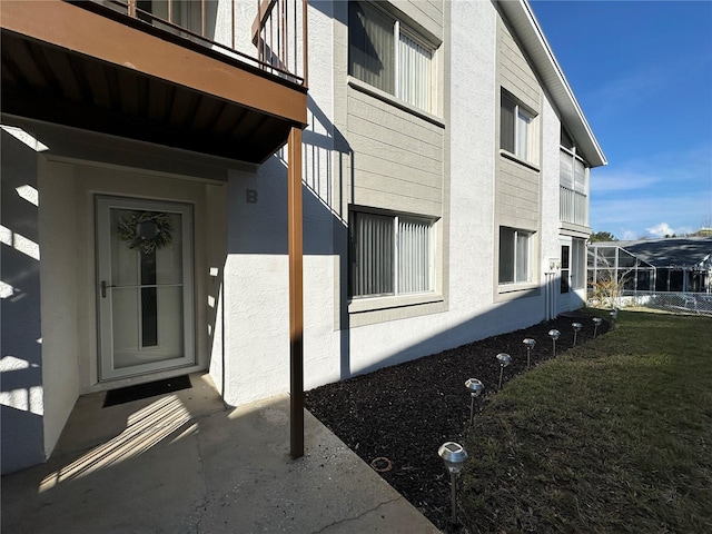 entrance to property featuring a balcony and a lawn