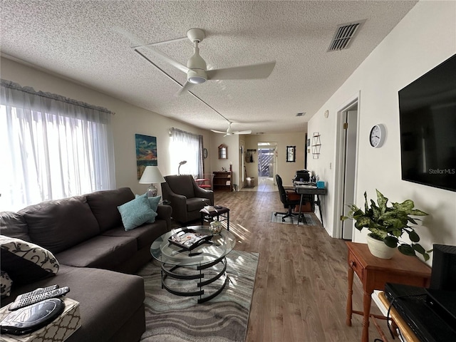 living room featuring hardwood / wood-style flooring, plenty of natural light, a textured ceiling, and ceiling fan