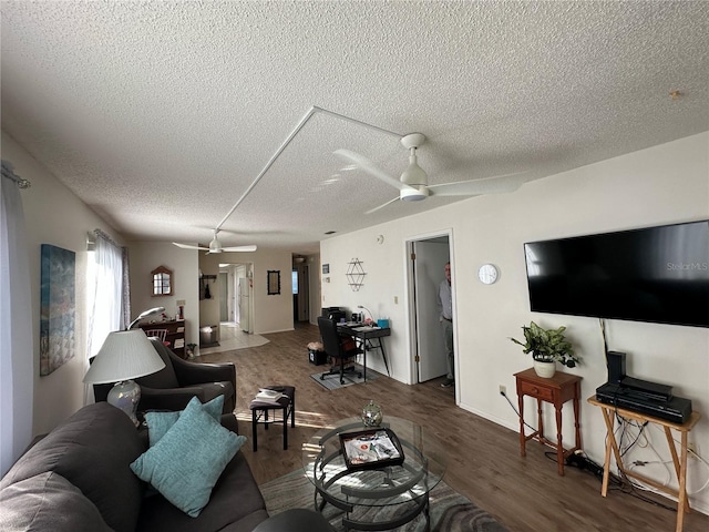 living room with dark wood-type flooring, ceiling fan, and a textured ceiling