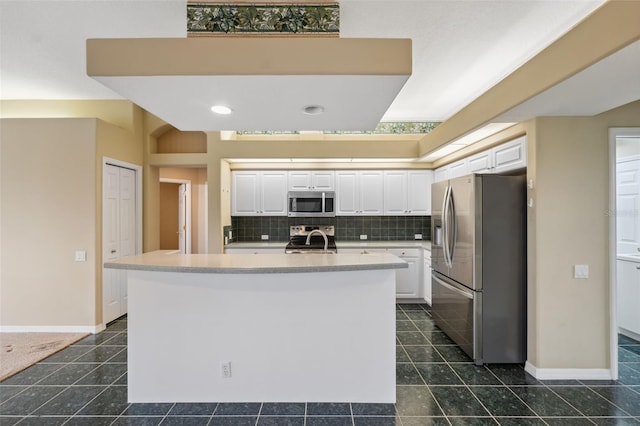 6112 Kinlock Ave, Spring Hill, FL 34608 - kitchen with appliances with stainless steel finishes, white cabinetry, tasteful backsplash, a sink, and dark tile patterned floors