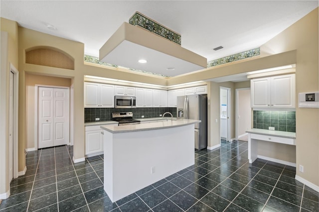 6112 Kinlock Ave, Spring Hill, FL 34608 - kitchen featuring stainless steel appliances, dark tile patterned flooring, white cabinetry, decorative backsplash, and light countertops