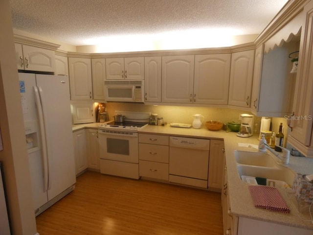 kitchen featuring light wood-type flooring, sink, a textured ceiling, and white appliances