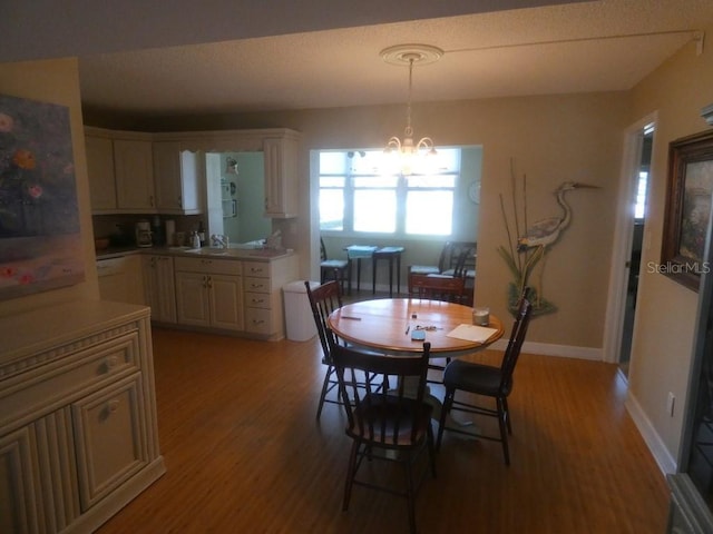 dining space with an inviting chandelier, sink, and light hardwood / wood-style flooring