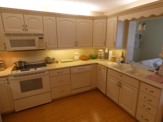 kitchen featuring sink, white appliances, and light wood-type flooring