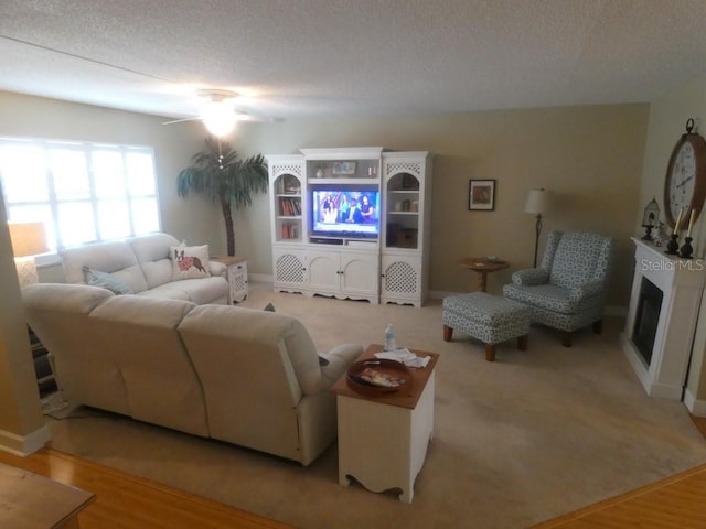 living room with ceiling fan, light hardwood / wood-style floors, and a textured ceiling