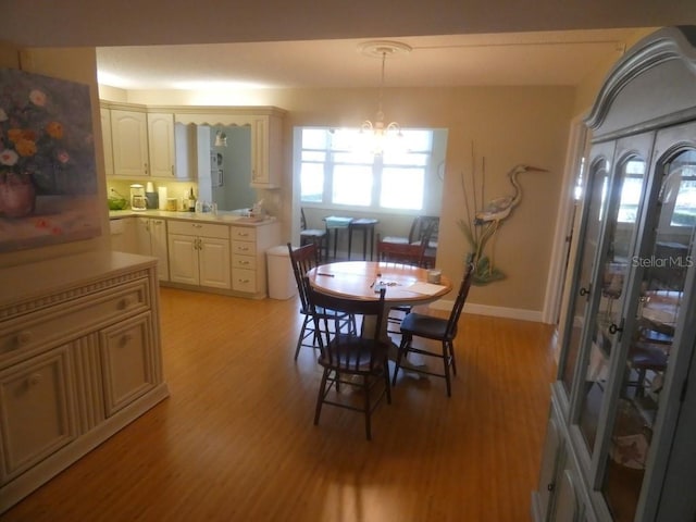 dining area with sink, light hardwood / wood-style flooring, and a chandelier