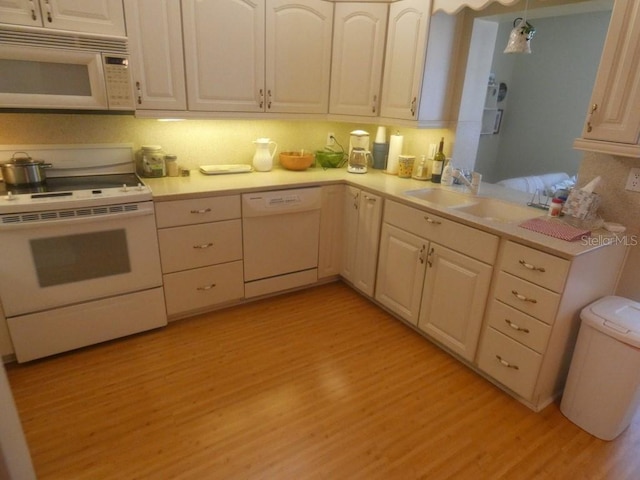 kitchen featuring light wood-type flooring, white appliances, and decorative light fixtures