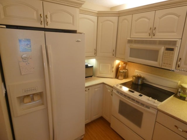 kitchen with white cabinetry, hardwood / wood-style floors, and white appliances