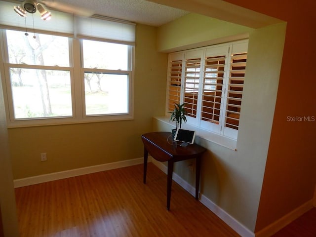 office area with a textured ceiling, wood finished floors, and baseboards