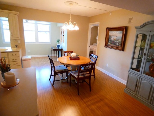 dining room with baseboards, a chandelier, visible vents, and light wood-style floors