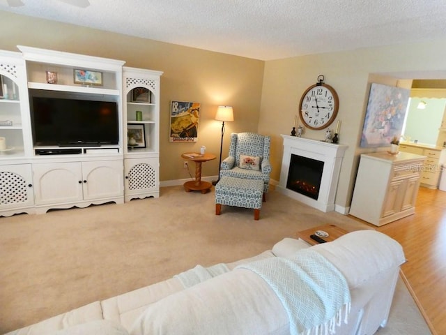 living room with light carpet, a warm lit fireplace, baseboards, and a textured ceiling