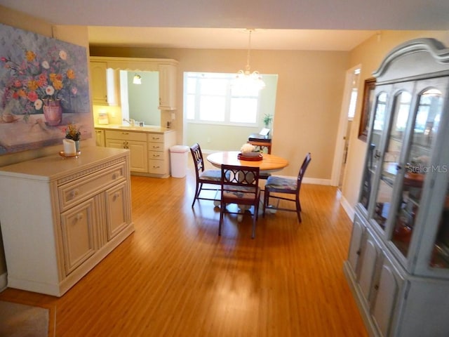 dining space with light wood finished floors, an inviting chandelier, and baseboards