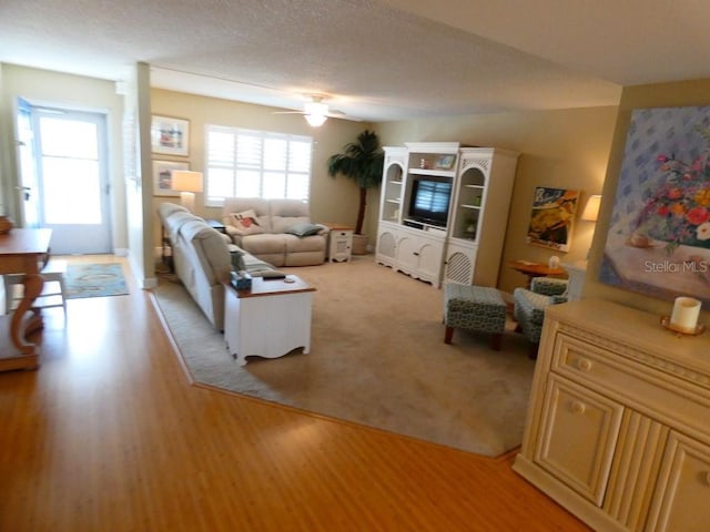 living area featuring a healthy amount of sunlight, light wood-type flooring, a textured ceiling, and a ceiling fan