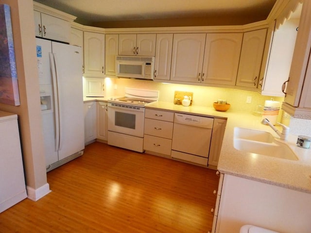 kitchen featuring light countertops, white appliances, light wood-type flooring, and a sink