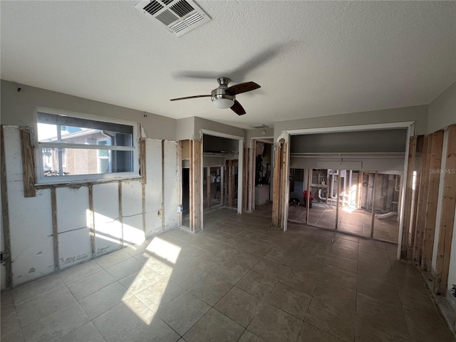 spare room featuring ceiling fan, tile patterned floors, and a textured ceiling