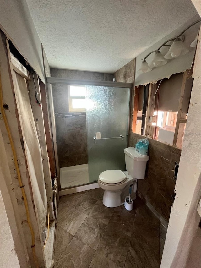 bathroom with an enclosed shower, a textured ceiling, and toilet