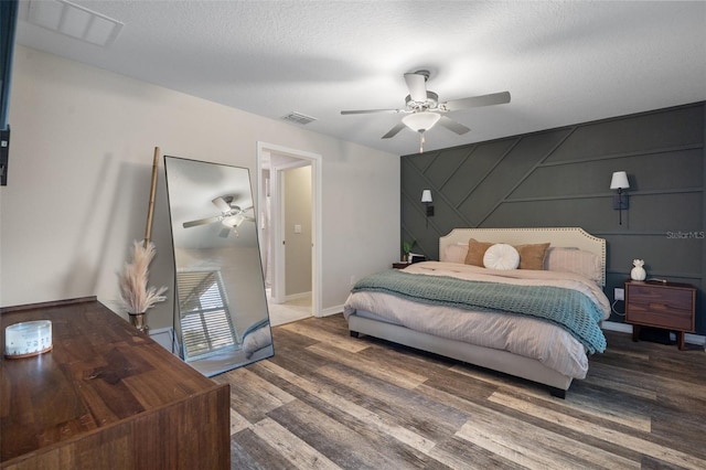 bedroom featuring ceiling fan, hardwood / wood-style floors, and a textured ceiling